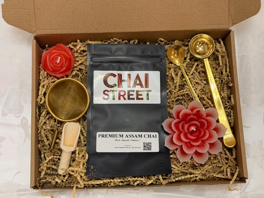 Assam Chai gift set including tea pack, gold scooping spoons, strainer, and flower-shaped candles