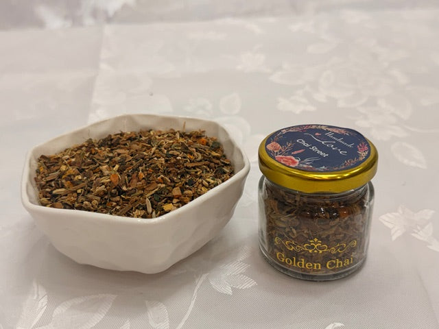 Chai Street Golden Chai in a small glass jar placed beside a bowl of loose herbal tea blend