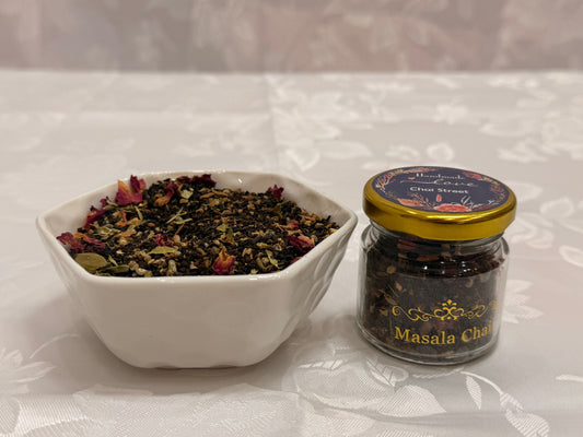 Masala Chai loose-leaf blend in a white bowl next to a glass jar labeled Masala Chai