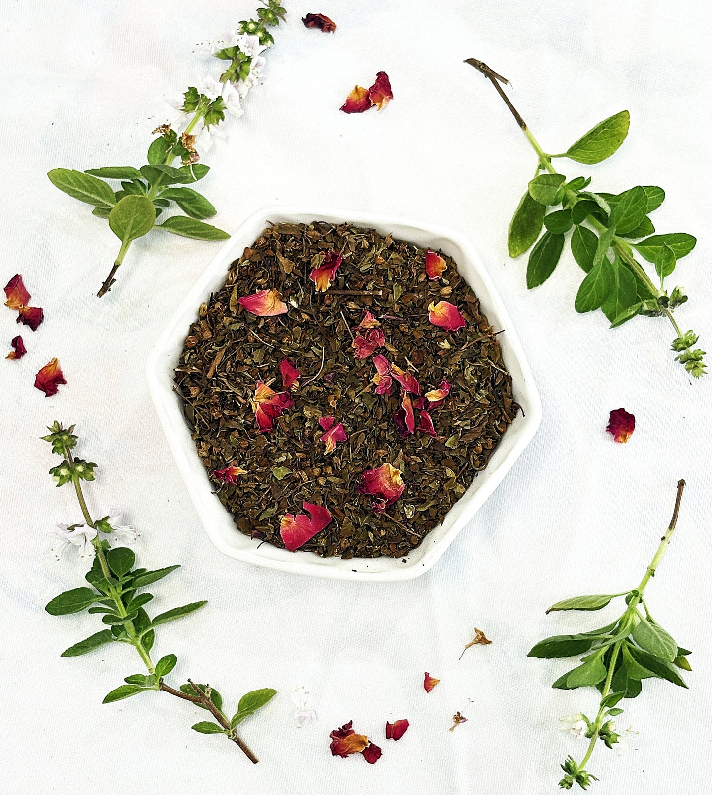 Chai Street Tulsi herbal tea blend in a bowl with rose petals and tulsi leaves on a white background