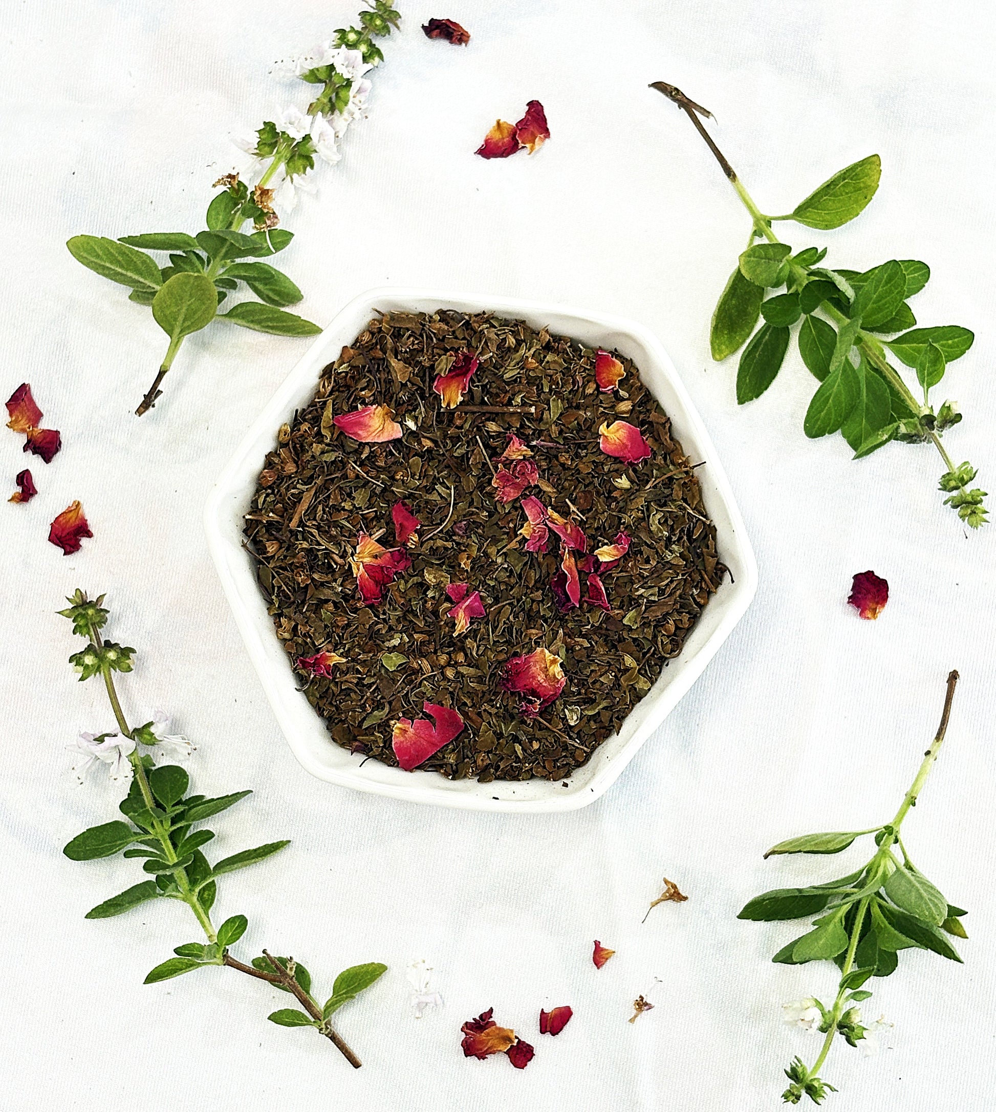 Chai Street Tulsi herbal tea blend in a bowl with rose petals and tulsi leaves on a white background